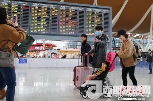 旅客帶著孩子前往辦票柜臺辦理登機手續(xù)?！∫罅⑶?攝