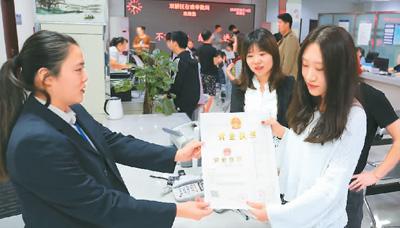 河北省承德市網(wǎng)絡(luò)代購經(jīng)營者陳晨(右)從工作人員手中接過帶有統(tǒng)一社會信用代碼的營業(yè)執(zhí)照。 劉環(huán)宇攝(人民圖片)